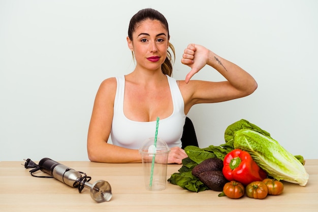 Jovem mulher caucasiana preparando um smoothie saudável com legumes