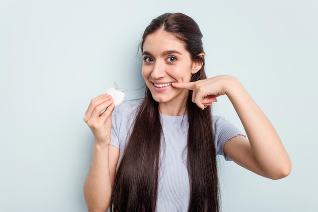 Jovem mulher caucasiana recebendo um clareamento dental isolado em fundo azul