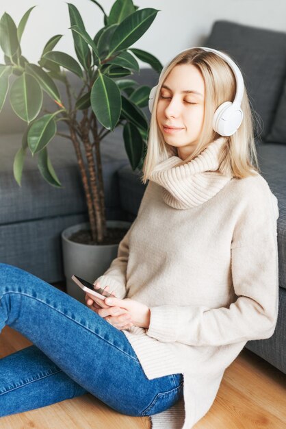 Jovem mulher caucasiana relaxa em casa com música