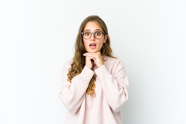 Jovem mulher caucasiana, rezando para ter sorte, espantada e abrindo a boca, olhando para frente.