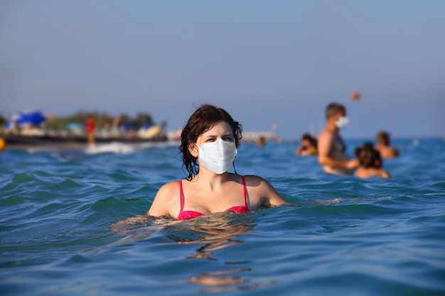 Jovem mulher caucasiana se aquecendo no mar com uma máscara protetora.