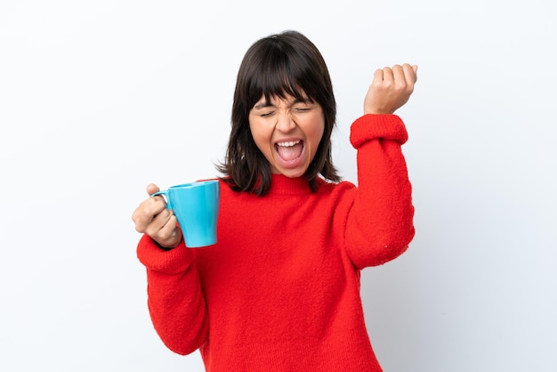 Foto jovem mulher caucasiana segurando a xícara de café isolada no fundo branco comemorando uma vitória