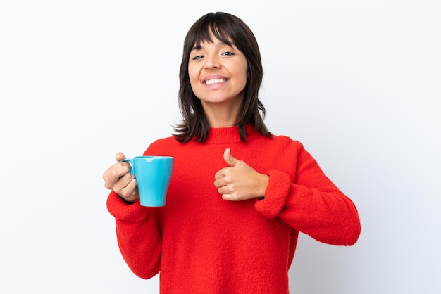 Jovem mulher caucasiana segurando a xícara de café isolada no fundo branco, dando um polegar para cima gesto