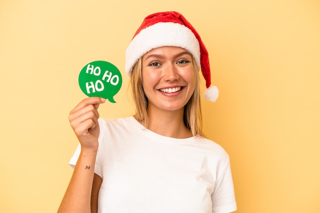 Jovem mulher caucasiana segurando adereços de natal isolados em fundo amarelo