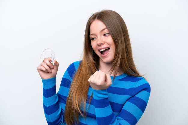 Foto jovem mulher caucasiana segurando aparelho invisível isolado no fundo branco comemorando uma vitória