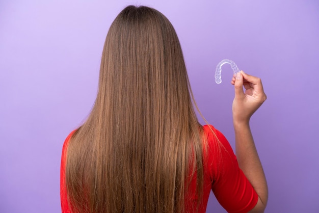 Foto jovem mulher caucasiana segurando aparelho invisível na posição traseira