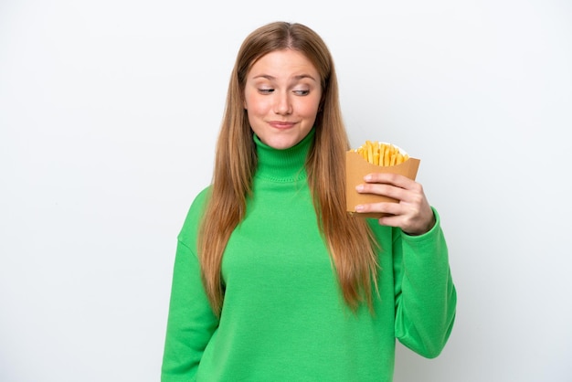 Jovem mulher caucasiana segurando batatas fritas isoladas no fundo branco com expressão feliz