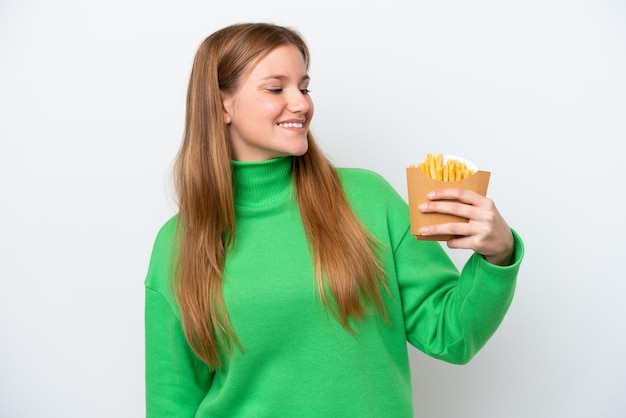 Jovem mulher caucasiana segurando batatas fritas isoladas no fundo branco com expressão feliz