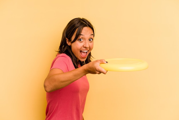 Jovem mulher caucasiana segurando frisbee isolado em fundo amarelo