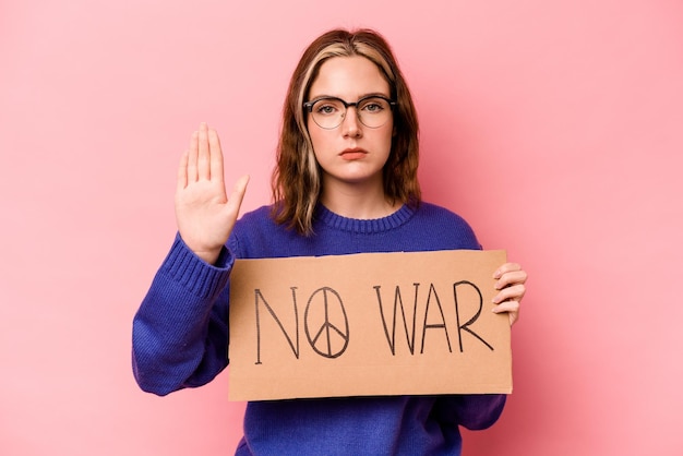 Jovem mulher caucasiana segurando nenhum cartaz de guerra isolado em fundo rosa