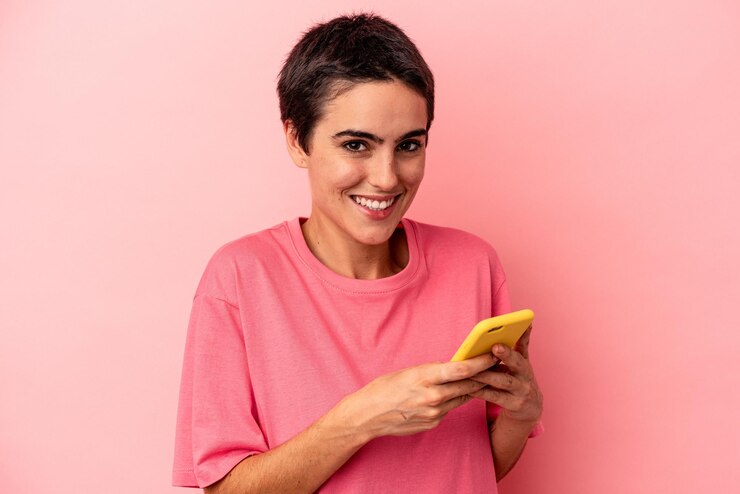 Foto jovem mulher caucasiana segurando o celular isolado no fundo rosa