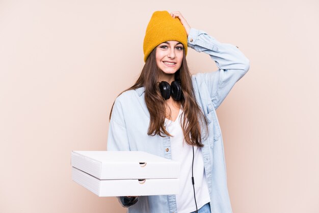 Jovem mulher caucasiana segurando pizzas isoladas sendo chocado, lembrou-se de uma reunião importante.