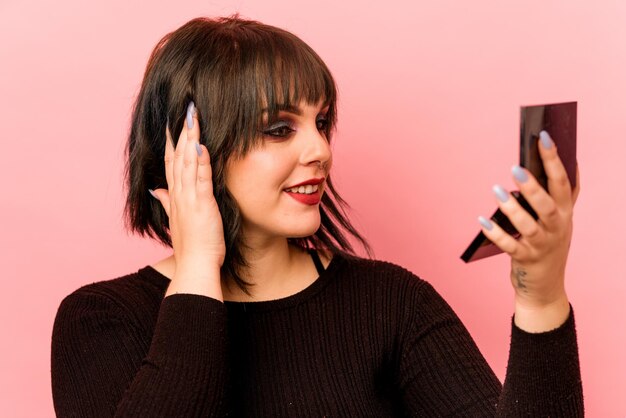 Jovem mulher caucasiana segurando sombras para os olhos isoladas em fundo rosa