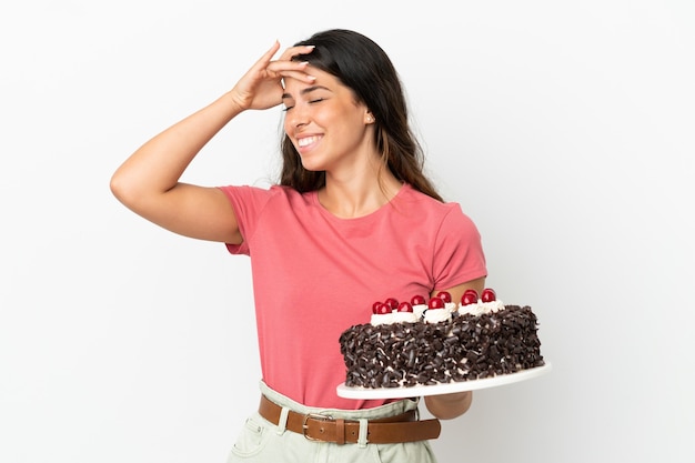 Jovem mulher caucasiana segurando um bolo de aniversário isolado no fundo branco e sorrindo muito