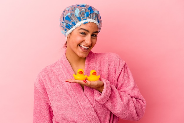 Jovem mulher caucasiana segurando um pato de plástico isolado em um fundo rosa