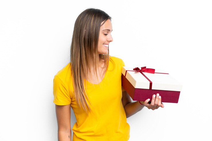 Foto jovem mulher caucasiana segurando um presente isolado no fundo branco com expressão feliz