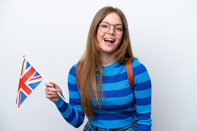 Jovem mulher caucasiana segurando uma bandeira do Reino Unido, isolada no fundo branco, com expressão facial de surpresa