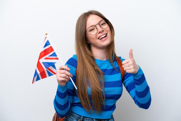 Jovem mulher caucasiana segurando uma bandeira do Reino Unido isolada no fundo branco com o polegar para cima porque algo de bom aconteceu