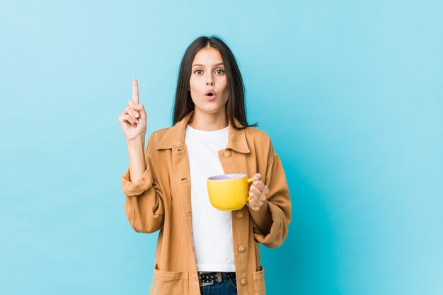 Jovem mulher caucasiana, segurando uma caneca de café, tendo uma ótima idéia, conceito de criatividade.