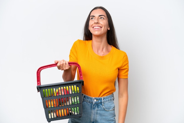 Foto jovem mulher caucasiana segurando uma cesta de compras cheia de comida