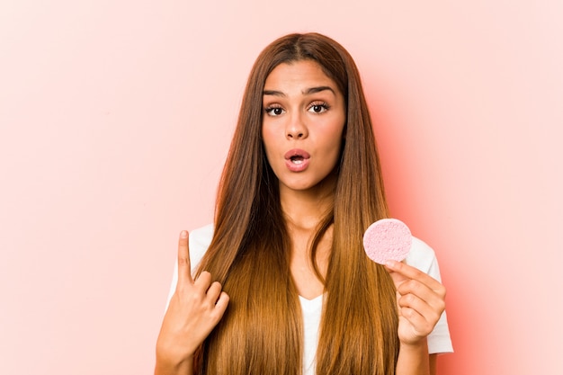 Jovem mulher caucasiana, segurando uma esponja facial, tendo uma ótima idéia, conceito de criatividade.