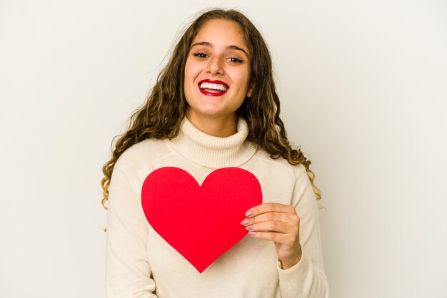 Foto jovem mulher caucasiana, segurando uma forma de dia dos namorados coração isolada, rindo e se divertindo.