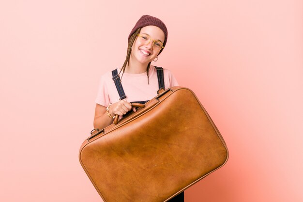 Jovem mulher caucasiana, segurando uma mala feliz, sorridente e alegre.