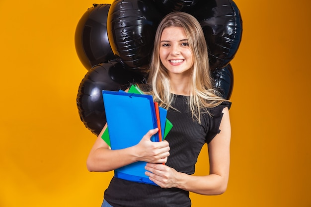 Jovem mulher caucasiana, sorrindo com cadernos nas mãos, indo para a universidade na sexta-feira negra. conceito de equilíbrio na educação