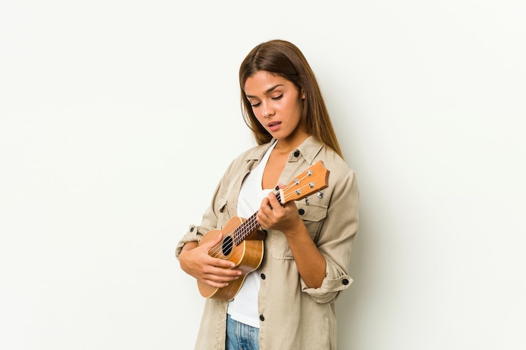 Foto jovem mulher caucasiana tocando ukelele isolada