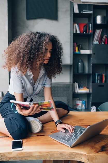 Jovem mulher caucasiana, trabalhando com o laptop no escritório moderno de coworking