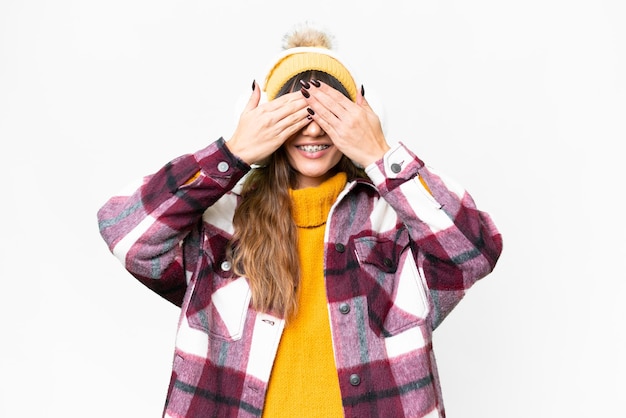 Foto jovem mulher caucasiana vestindo muffs de inverno sobre fundo branco isolado cobrindo os olhos com as mãos