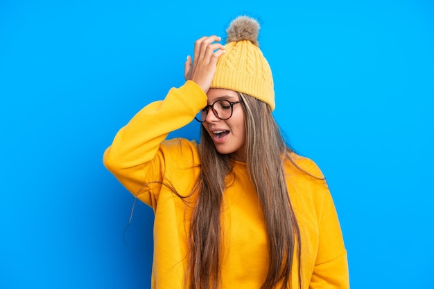 Jovem mulher caucasiana vestindo roupas de inverno isoladas em fundo azul percebeu algo e pretende a solução