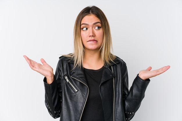 Jovem mulher caucasiana, vestindo uma jaqueta de couro preta confuso e duvidoso encolher os ombros os ombros para manter um espaço de cópia.