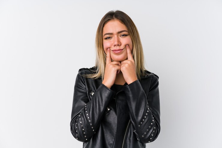 Foto jovem mulher caucasiana, vestindo uma jaqueta de couro preta, duvidando entre as duas opções.