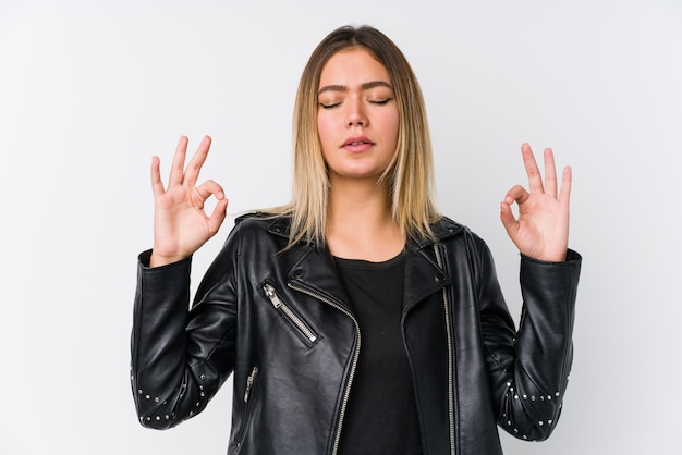 Jovem mulher caucasiana, vestindo uma jaqueta de couro preta relaxa após um duro dia de trabalho, ela está realizando ioga.