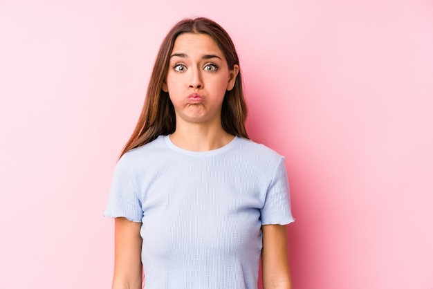 Jovem mulher caucasiana, vestindo uma roupa de esqui isolada sopra bochechas, tem expressão cansada. Conceito de expressão facial.