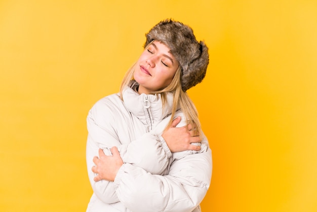 Jovem mulher caucasiana, vestindo uma roupa de inverno isolada abraços, sorrindo despreocupada e feliz.