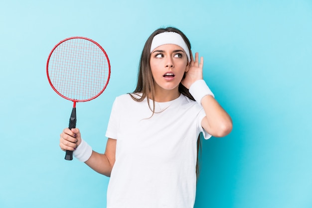 Jovem mulher caucasic jogando badminton, tentando ouvir uma fofoca.