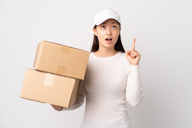 Jovem mulher chinesa entregadora em branco isolado apontando com o dedo indicador uma ótima ideia