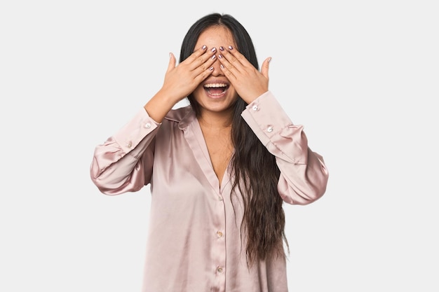 Jovem mulher chinesa isolada cobre os olhos com as mãos sorri amplamente esperando uma surpresa