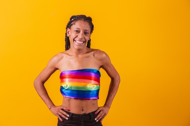 Jovem mulher cobrindo com a bandeira do orgulho LGBT. Sozinho. Um. Mantendo o punho erguido, cobrindo a bandeira LGBT. LGBT + bandeira em fundo amarelo.