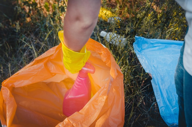 Jovem mulher coletando lixo e colocando em saco de lixo plástico - conceito de poluição ambiental