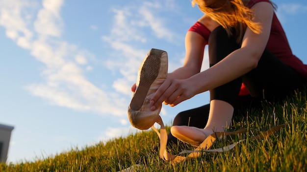 Jovem mulher colocou suas sapatilhas sentadas na grama verde