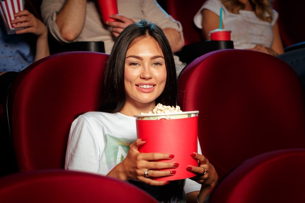 Jovem mulher com amigos assistindo filme no cinema