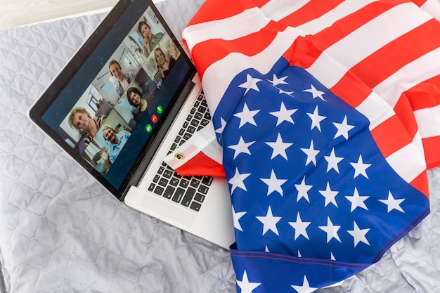 Jovem mulher com bandeira dos EUA usando um computador portátil, dia da independência online.