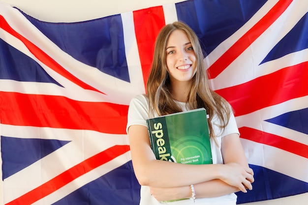 Jovem mulher com bandeiras de países de língua inglesa. Aluna inglesa com a bandeira britânica ao fundo. Inglês, aprender, estudar.