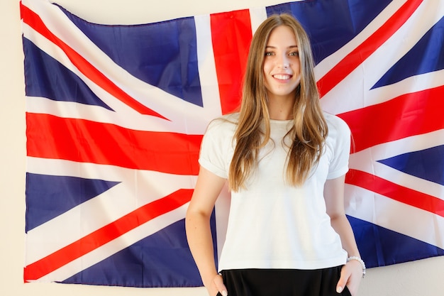 Jovem mulher com bandeiras de países de língua inglesa. Aluna inglesa com a bandeira britânica ao fundo. Inglês, aprender, estudar.