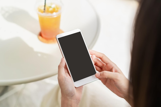 Jovem mulher com bebidas, usando telefone celular e relaxando em um café. Estilo de vida moderno