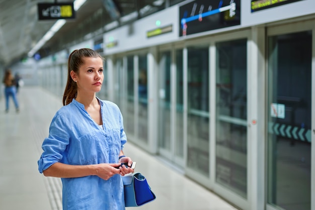 Jovem mulher com bolsa na estação de metrô.