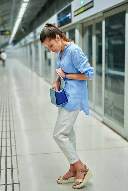 Jovem mulher com bolsa na estação de metrô.